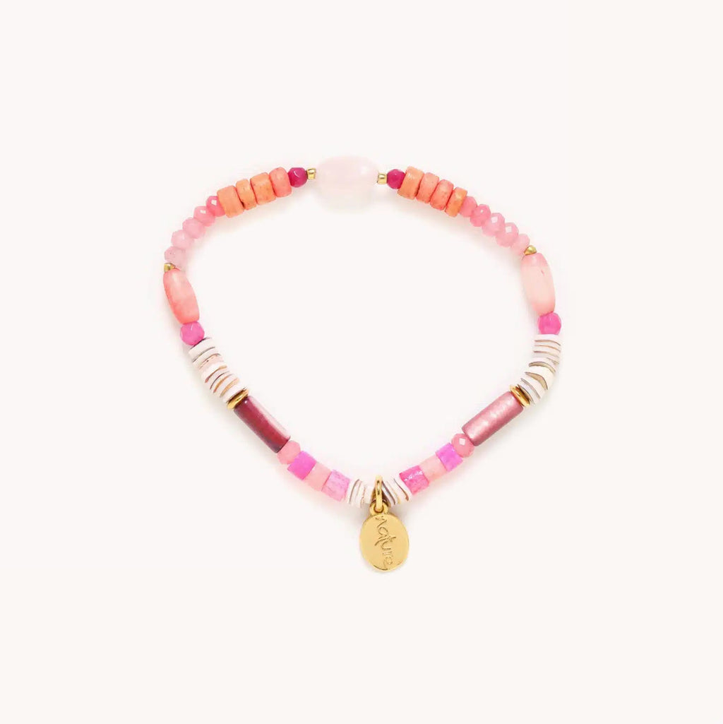 Bracelet composé de perles ovoïdes en quartz rose et de perles longues en bois teinté associées à des perles et rondelles de plusieurs tailles en matière naturelle à dominante rose orangé : corail, coquillage, nacre teintée. Les perles sont séparées par de petites perles ou rondelle en métal.
