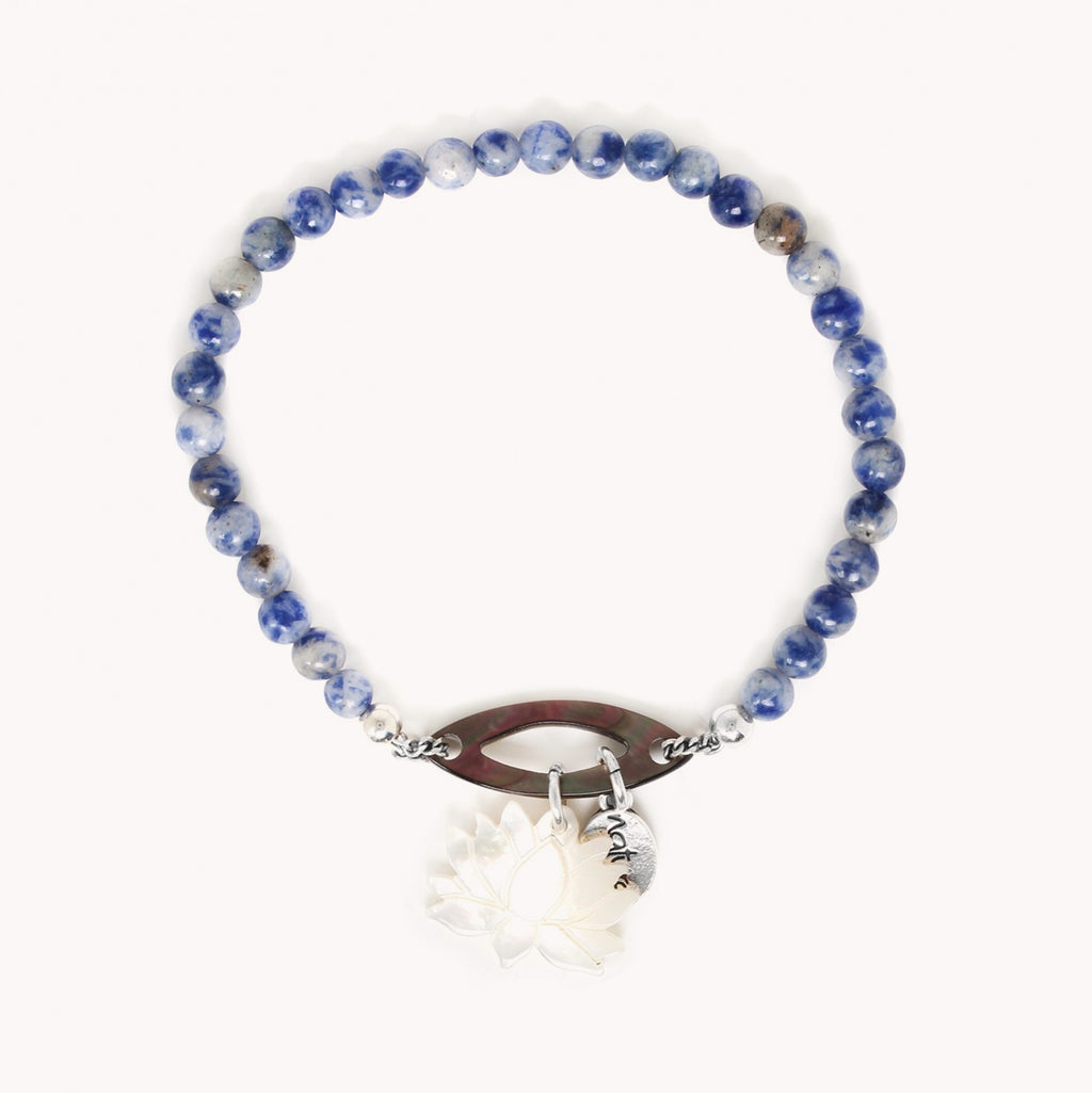 Bracelet composé de perles rondes en pierre naturelle, le jaspe bleu, et d'un médaillon, de nacre brune en forme de navette ajourée, sur lequel est suspendue une breloque en forme de lotus de nacre blanche.