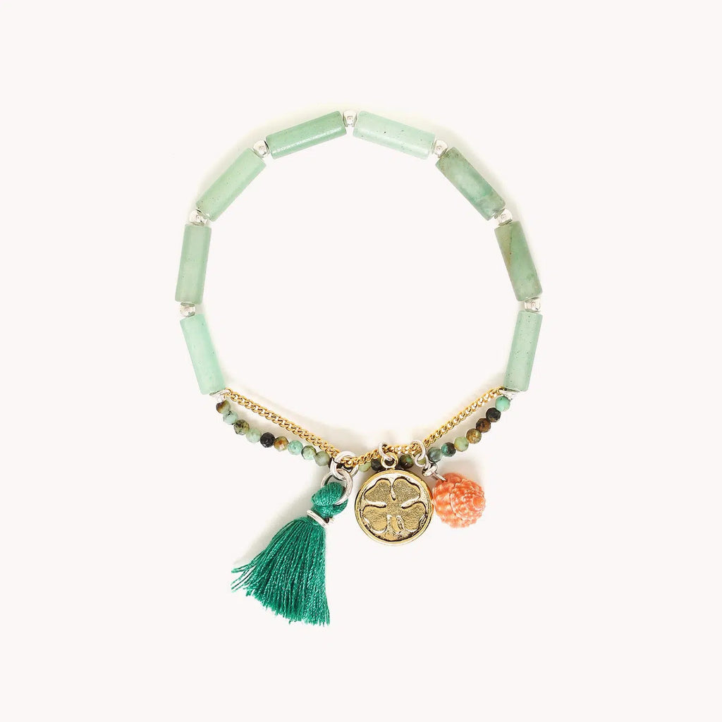 Bracelet extensible composé de perles longues en aventurine verte, de petites perles rondes facettées en turquoise africaine et d'une chainette dorée à l'or fin dotée d'une médaille avec un motif feuille de trèfle, d'un coquillage et d'un pompon vert à franges.
